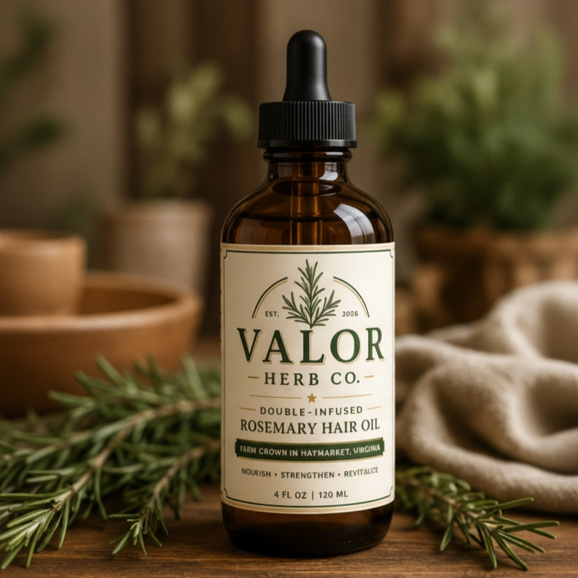 Bottle of Valor Herb Co. rosemary hair oil with a dropper on a wooden surface with greenery.