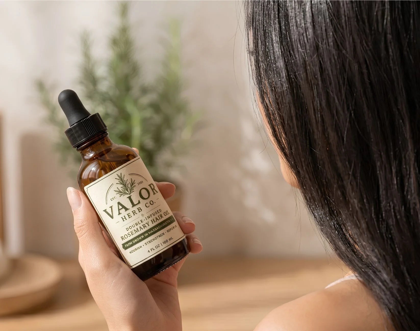 Hand holding a bottle of Valon Herb Co. hair oil with a blurred background